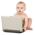 Baby sitting with a laptop, looks curious.